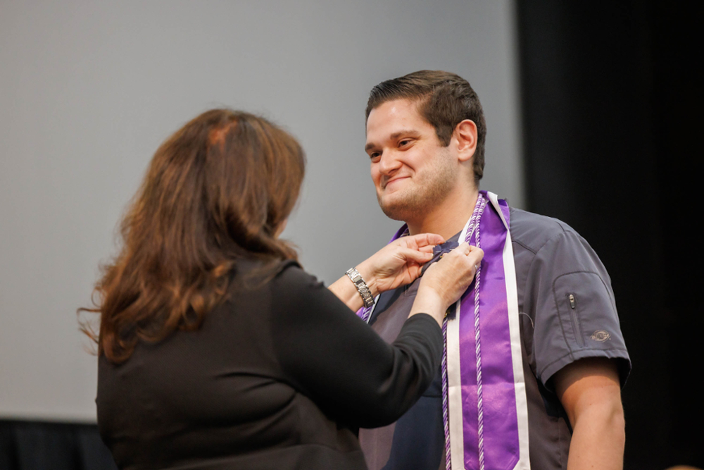 Jacob Alford getting pinned by dean during Pinning Ceremony.